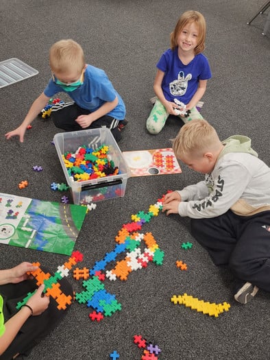 Boys on carpet connecting puzzle pieces